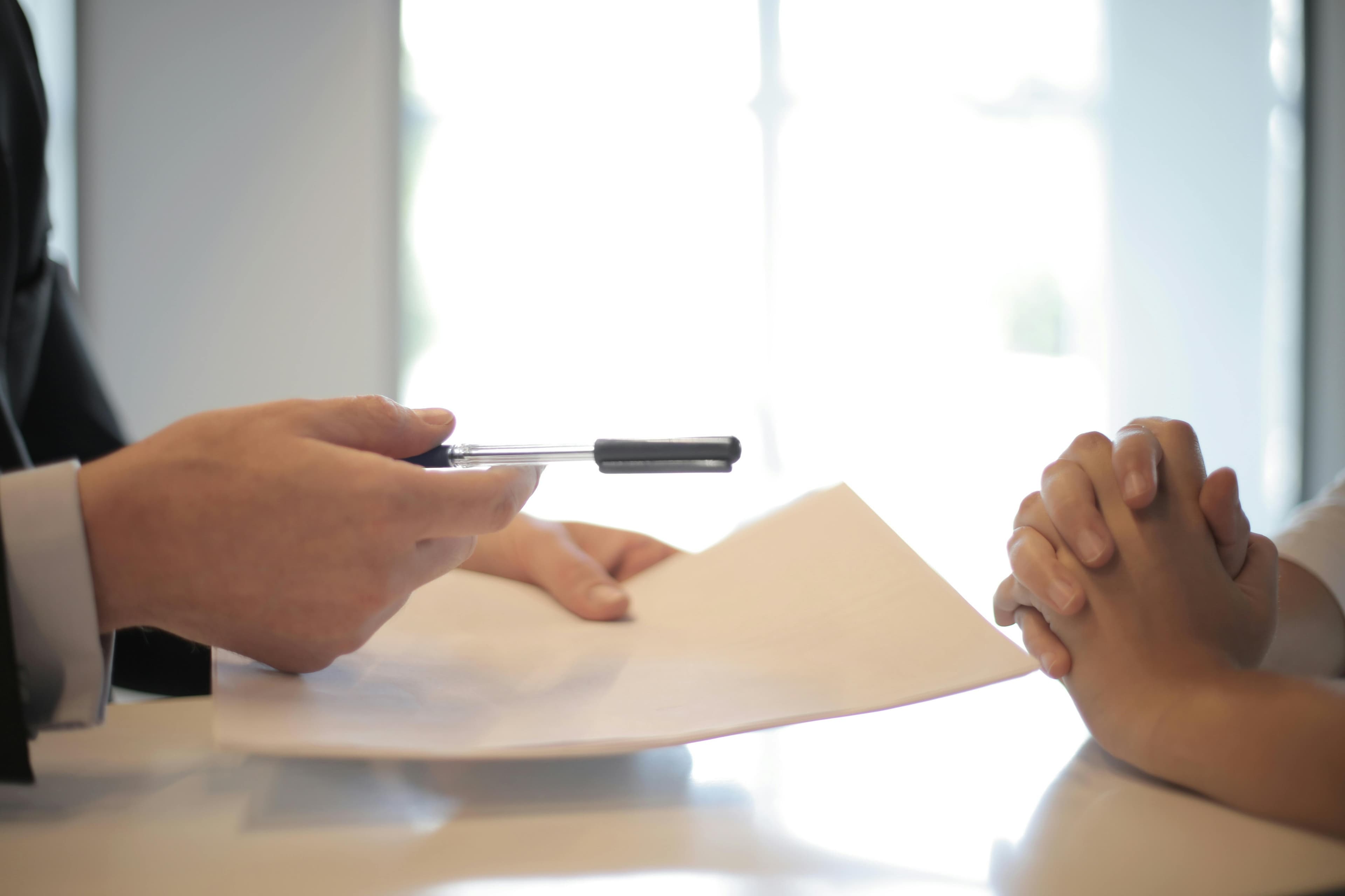 Loan papers and a pen passed across a desk to a customer